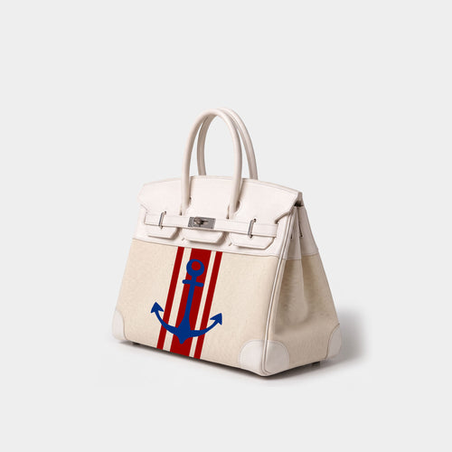An off-white leather handbag with silver hardware, featuring a red and white vertical stripe pattern on the front panel and a blue anchor graphic in the center.