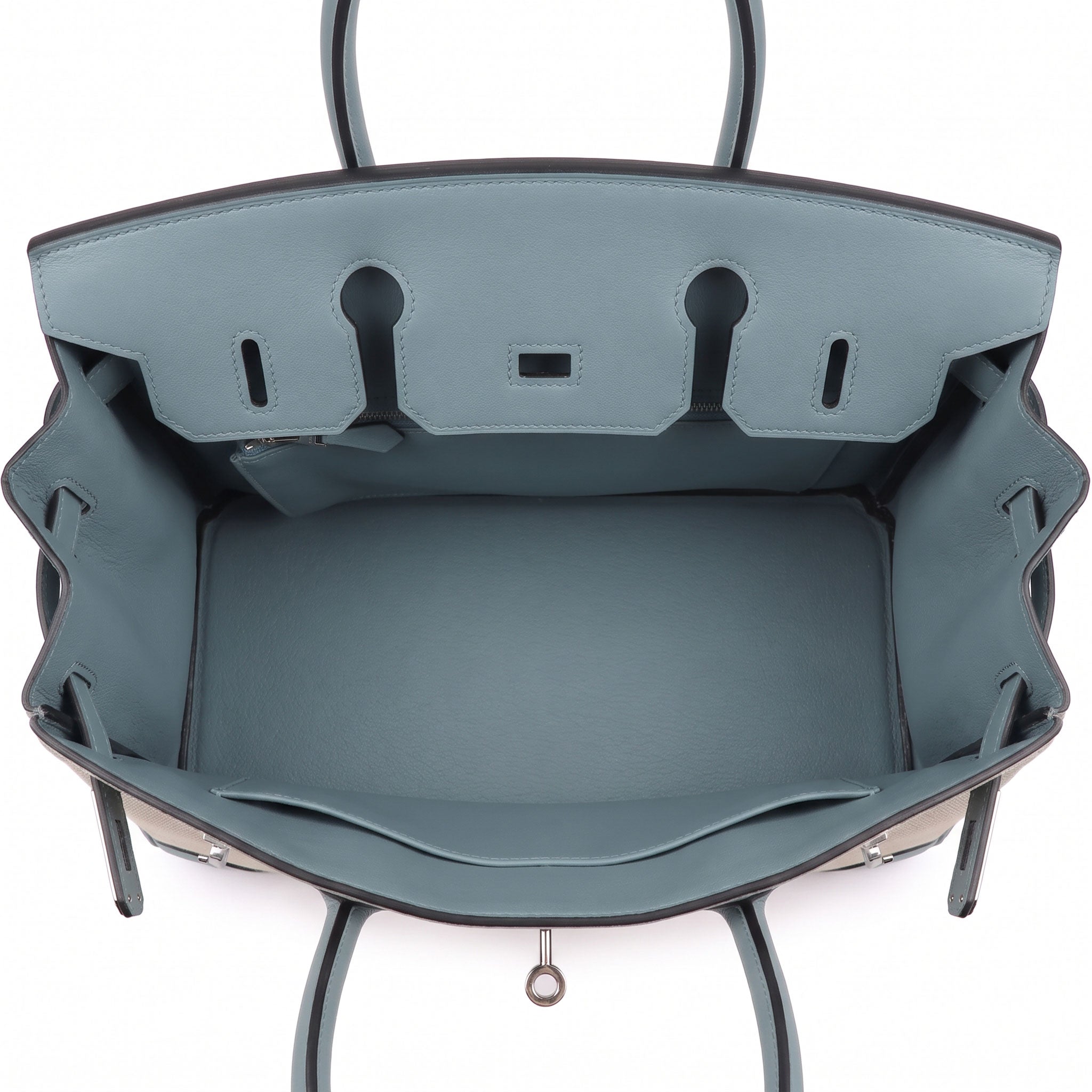 The interior of a structured leather handbag shown from above, featuring a dusty slate blue lining with dark brown or black edging and silver-tone hardware.