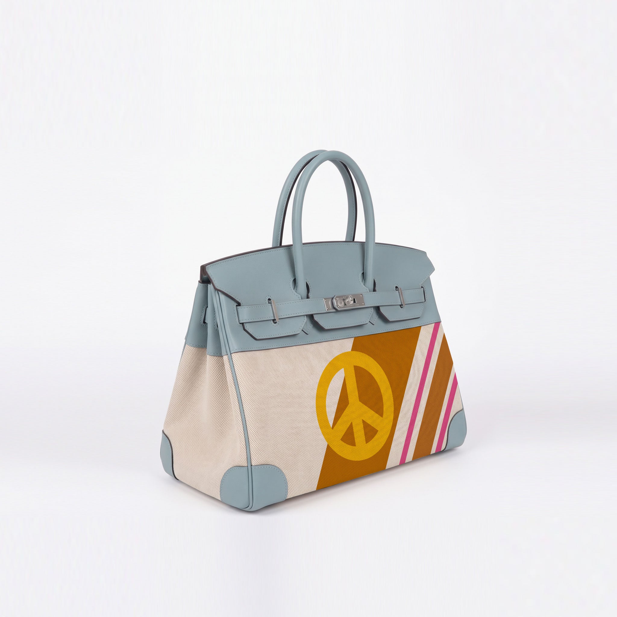 A structured leather handbag with a muted blue-gray top and handles, beige canvas side panels, a large yellow peace sign on a brown panel, and pink and blue diagonal stripes, shown on a clean white background.