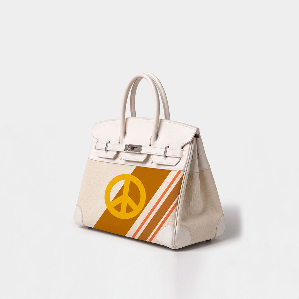 A structured cream-colored leather handbag with silver-tone hardware, featuring a yellow peace sign and diagonal orange and yellow stripes on the front panel, set against a light gray studio background.