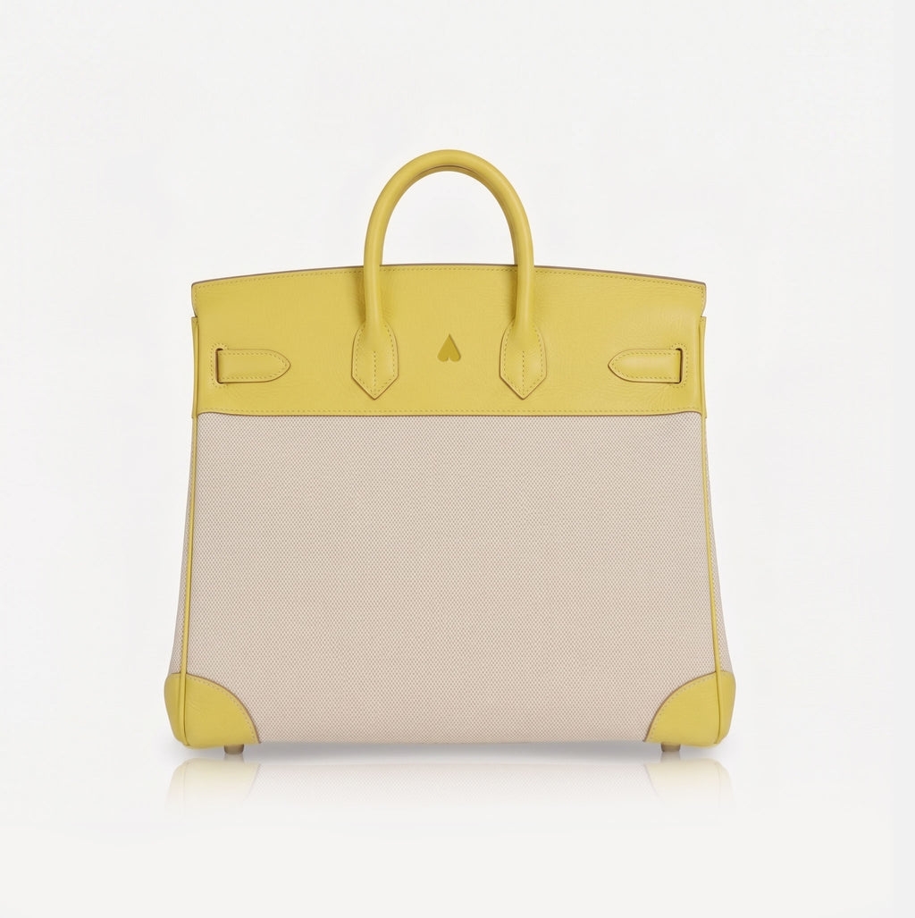 A structured handbag with a bright yellow leather top handle, trim, and corner protectors, paired with a large light beige canvas front panel, shown against a plain white background.