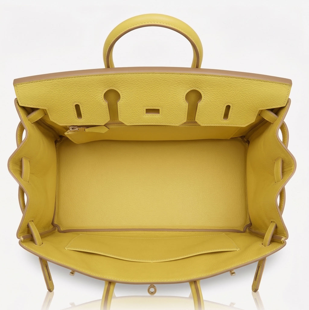 A bright yellow textured leather handbag shown open from the top, displaying its interior lining, handle, and interior hardware against a clean white background.