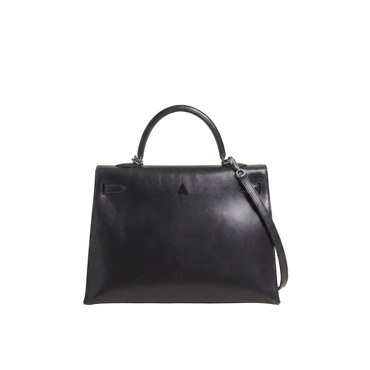 A black leather top-handle handbag with a structured rectangular silhouette, a detachable shoulder strap, and small silver-tone hardware, photographed against a plain light gray studio background.