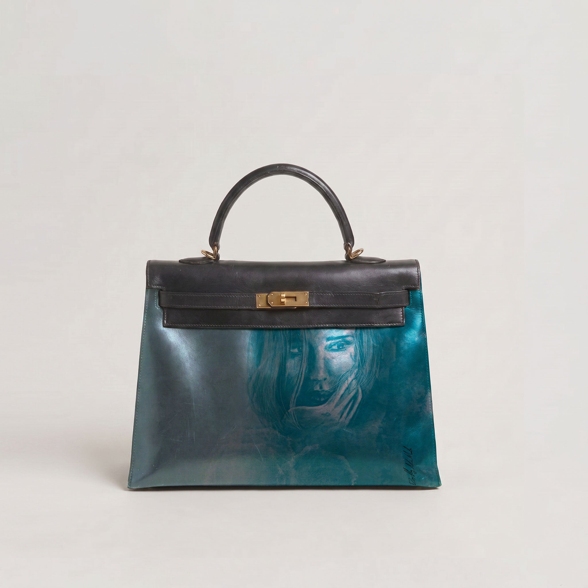 A structured leather handbag with a glossy teal and blue marbled finish, a black top handle and flap, and a gold turn-lock clasp, featuring a faint artistic portrait printed on the front.