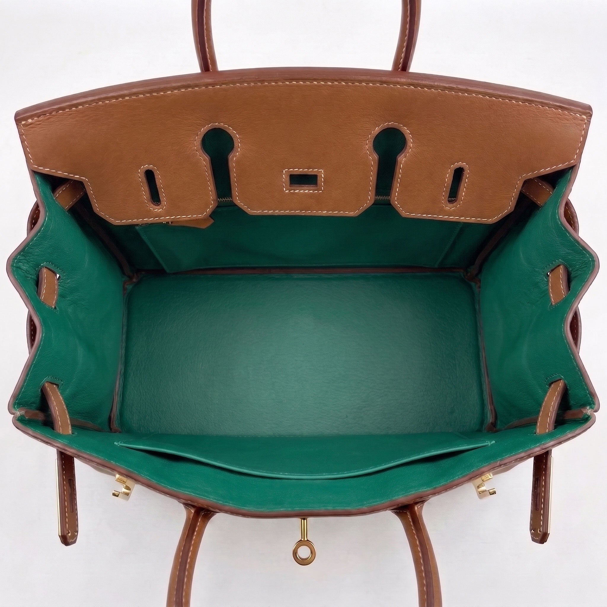 A top-down view of a structured leather handbag showing a tan exterior and a contrasting green interior lining, with gold-tone hardware visible.