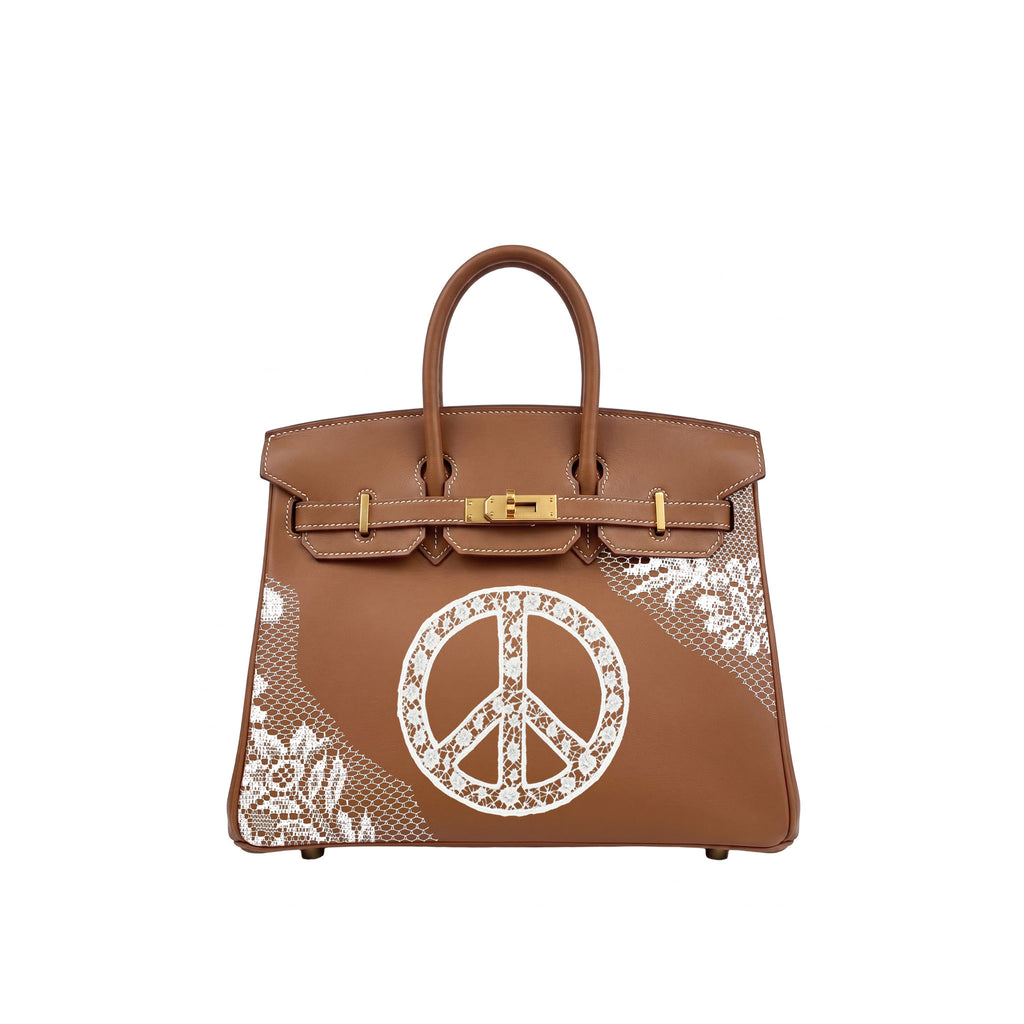 A brown leather handbag with gold-tone hardware, featuring a large white peace sign motif and white floral lace-like patterns on the front, set against a plain white background.