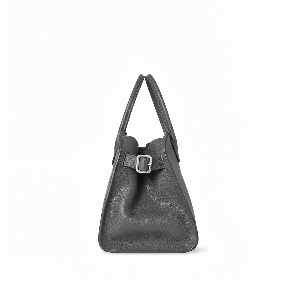 A dark grey full grain leather handbag with dual top handles and a decorative strap detail with a silver buckle, shown against a plain white background.