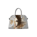 A structured silver handbag with dual top handles, featuring a printed artistic portrait of a woman's face in brown, beige, and grey tones on the front.