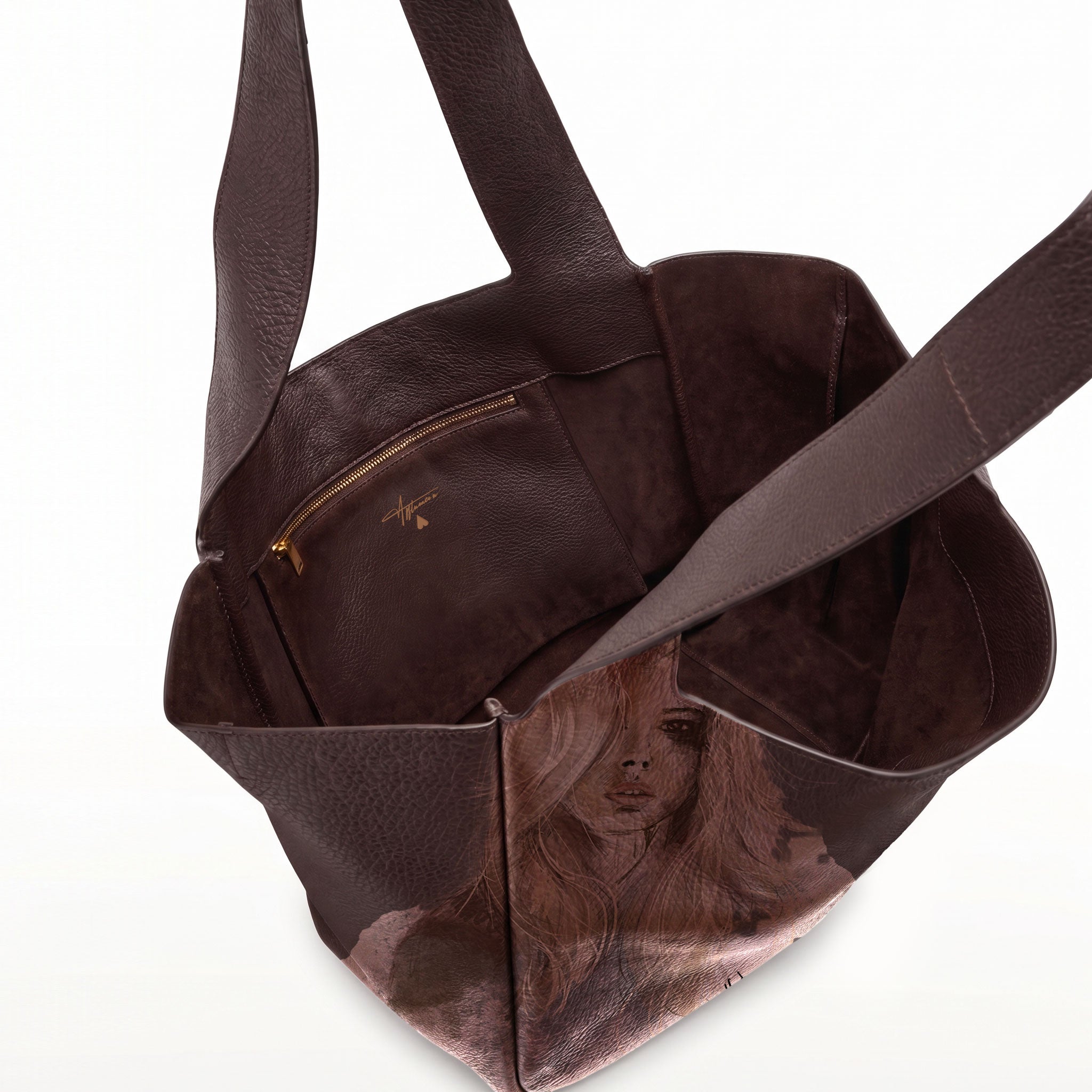 A dark brown leather tote bag with a printed portrait of a woman on the lower front panel and a zippered pocket inside, shown on a white background.