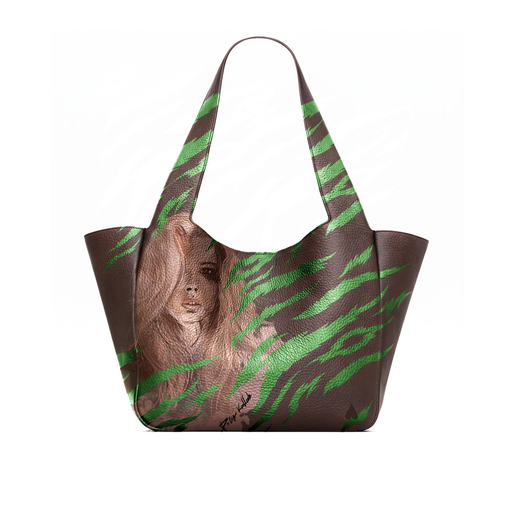 A brown full grained leather tote bag featuring a printed portrait of a woman with long brown hair and green tiger-stripe patterns across the front and handles, shown against a plain white background.